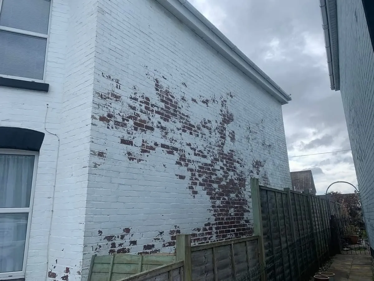 Peeling paint on a brick wall before redecoration in Hayle